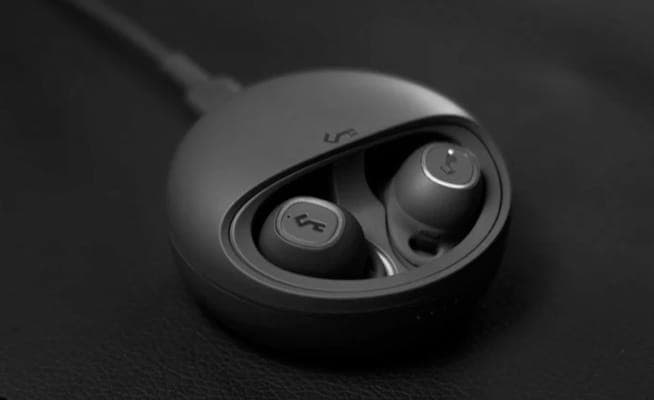 A plugged-in charging case with truly wireless earbuds inside, all black